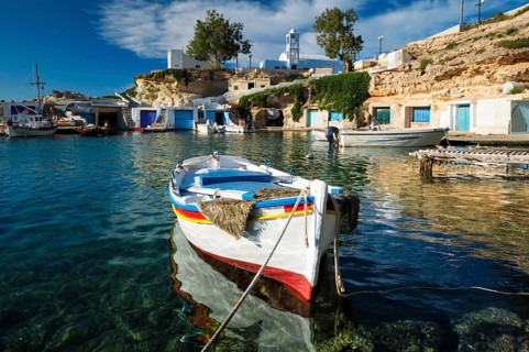 Fishing boats moored in crystal clear turquoise sea water in harbour in Greek fishing village of Mandrakia
