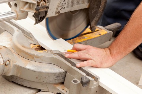 Contractor using circular saw cutting new baseboard for renovation