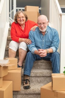 Senior couple resting on stairs surrounded by moving boxes