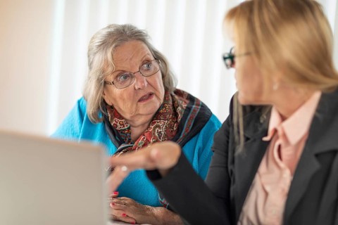 Woman helping senior adult lady on laptop computer