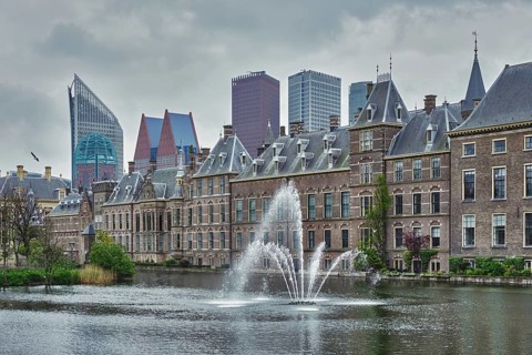 View of the Binnenhof House of Parliament and the Hofvijver lake with downtown skyscrapers in background. The Hague