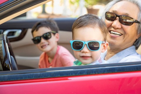 Chinese granfather and mixed-race children playing in parked car