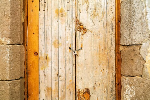 Rusty padlock locking old wooden door with a chain