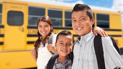 Young hispanic boys and girl walking near school bus