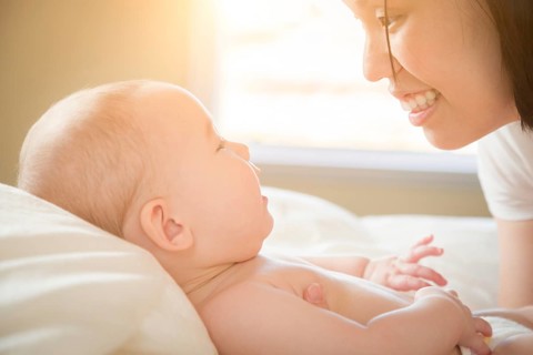 Young mixed-race chinese and caucasian baby boy laying in his bed with his mother