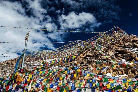 Tibetan prayer flags of Buddhism with Buddhist mantra on it on top of Himalayan pass Khardung La