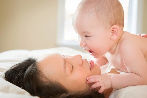 Young mixed-race chinese and caucasian baby boy laying in his bed with his mother