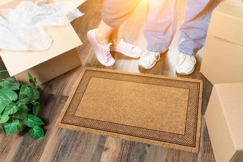 Man and woman standing near blank welcome mat