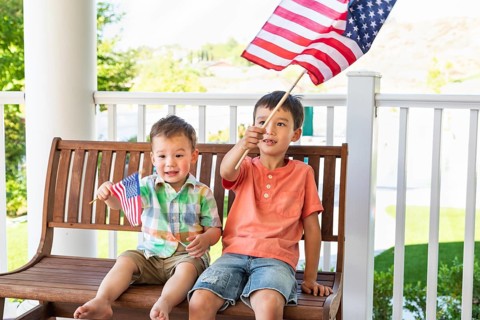 Young mixed-race chinese and caucasian brothers playing with american flags