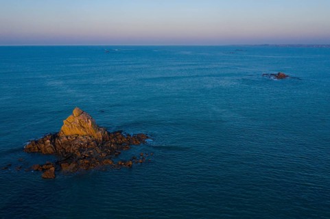 Aerial view of rock formations in the sea in front of the sandy beach Ker Emma shortly in front of sunset