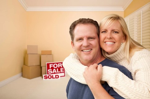 Happy affectionate couple in room of new house with only boxes on the floor