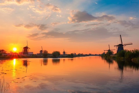 Netherlands rural landscape with windmills at famous tourist site Kinderdijk in Holland on sunset with dramatic sky