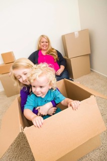 Playful young family in empty room playing with moving boxes