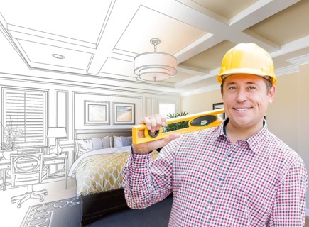 Smiling contractor in hard hat with level over custom bedroom drawing and photo combination