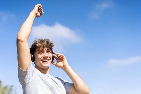 Young man listening to music outdoors with headphones. Expression of happiness