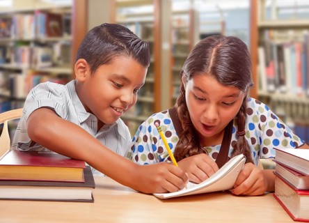 Hispanic boy and girl having fun studying together in the library