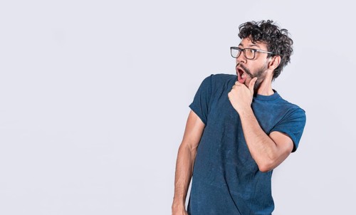 Amazed young man with hand near open mouth
