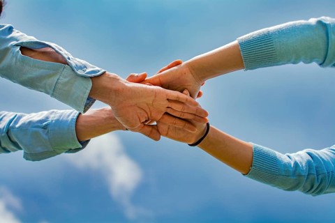 Concept of one hand over another forming a team