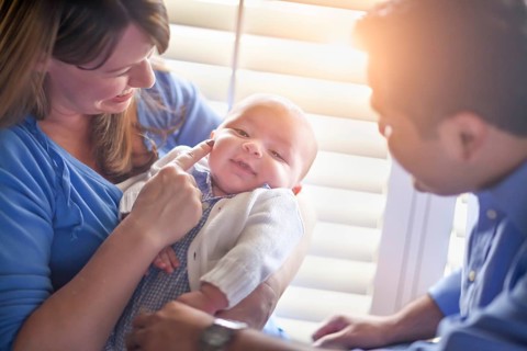 Happy mixed-race couple enjoying their newborn son in the light of the window