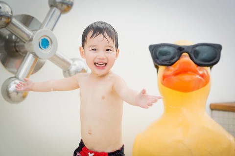 mixed-race boy having fun at the water park with large rubber duck in the background