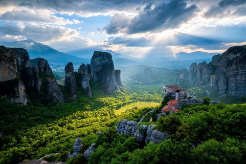 Sunset over monastery of Rousanou and Monastery of St. Nicholas Anapavsa in famous greek tourist destination Meteora in Greece on sunset with sun rays and lens flare and dramatic sky