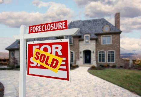 Sold foreclosure home for sale sign and house with dramatic sky background