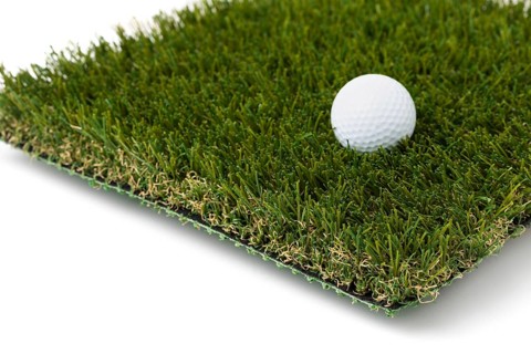 Golf ball resting on section of artificial turf grass on white background
