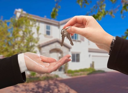 Handing over the new house keys with home in the background