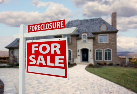 Foreclosure home for sale sign and house with dramatic sky background