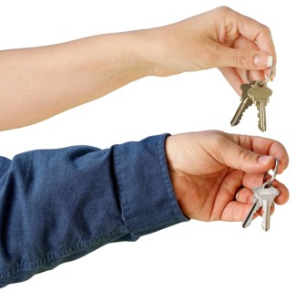 Man and woman handing over house keys on a white background with clipping path
