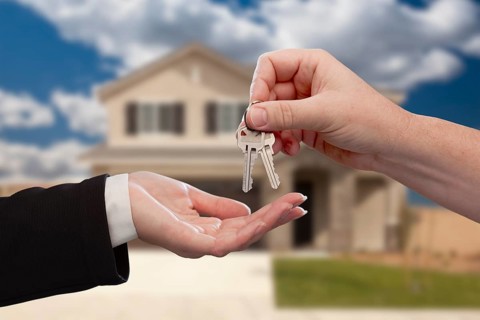 Handing over the house keys in front of a beautiful new home