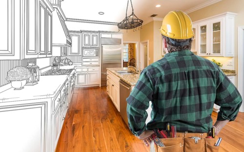 Male contractor with hard hat and tool belt looking at custom kitchen drawing photo combination on white