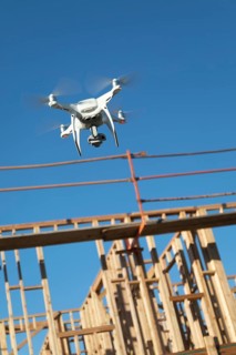 Drone quadcopter flying and inspecting wood framing at construction site