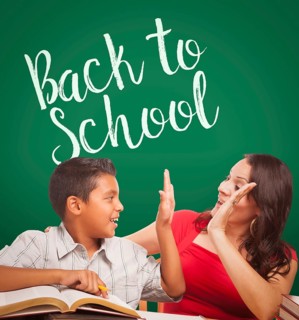 Back to school written on chalk board behind hispanic young boy and famale adult studying