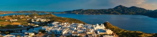 Panorama of Plaka village on Milos island with traditional greek white houses on sunset