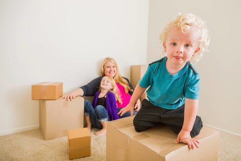 Playful young family in empty room playing with moving boxes