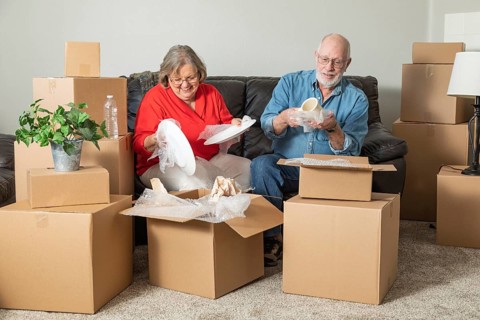 Senior adult couple packing or unpacking moving boxes