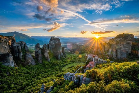 Sunset over monastery of Rousanou and Monastery of St. Nicholas Anapavsa in famous greek tourist destination Meteora in Greece on sunset with sun rays and lens flare