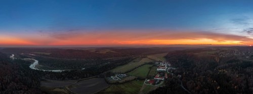 Orange glowing sunset behind Schaeftlarn Monastery and the meandering Isar River