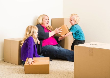 Playful young family in empty room playing with moving boxes