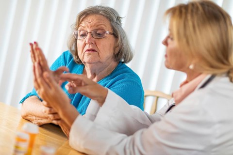 Female doctor talking with senior adult woman about hand therapy