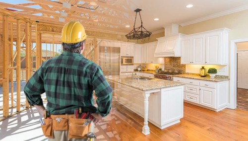 Contractor standing in front custom kitchen construction framing gradating into finished build