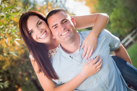 Happy romantic caucasian couple piggyback riding in the park