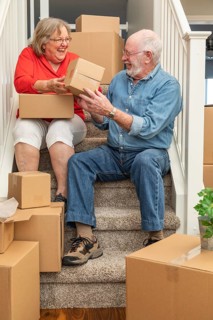 Senior couple resting on stairs surrounded by moving boxes