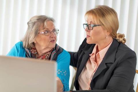Woman helping senior adult lady on laptop computer