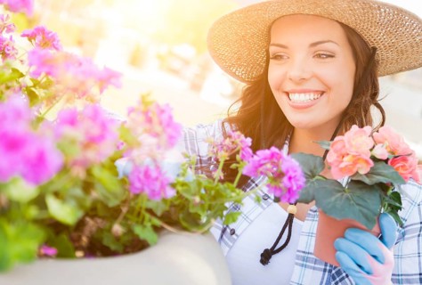 Happy young adult woman wearing hat and gloves gardening outdoors