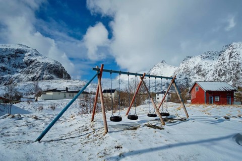Children playground with swings made of car tires in winter
