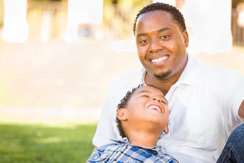 Happy african american father and mixed-race son playing at the park