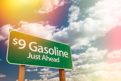 $9 gas green road sign against cloudy sky