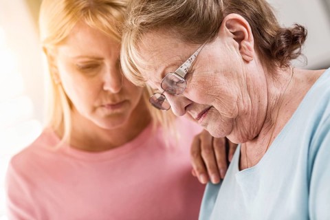 Young adult woman consoles sad senior adult female